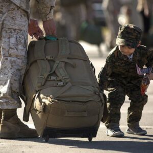 Little boy helps his deploying military dad with his gear bag