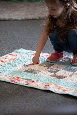 Military child looking at her Operation Kid Comfort Quilt from ASYMCA