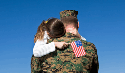 Military dad hugging military child with American flag