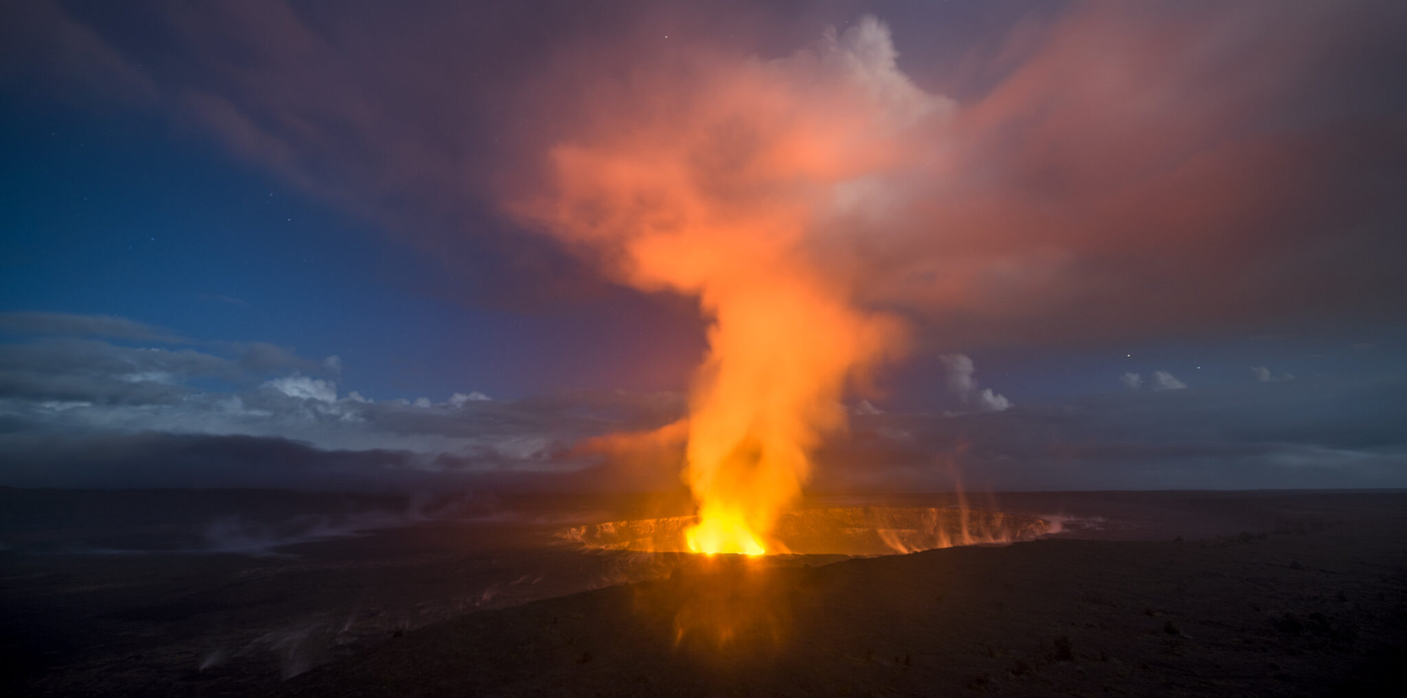 A 30-second captures the glowing lava lake in the caldera of Hawaii's Kilauea Volcano as it bounces light off of the haze drifting by in the sky.