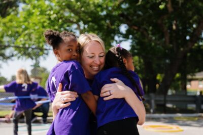 Military kids hugging ASYMCA staff member of Operation Little Learners program