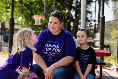 ASYMCA staff member listening to military kids in an outdoor setting