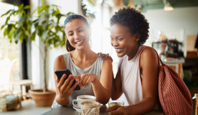 Two military spouses catching up over coffee and laughing together.