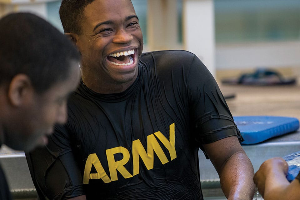 Soldier it PT uniform laughs with fellow soldiers in Gym during Workout