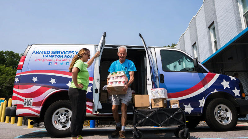 Armed Services YMCA staff unload boxes of food from a van.