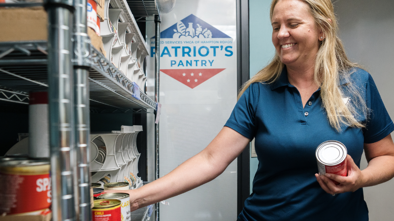Armed Services YMCA staff member stocks shelves in a food pantry for military families