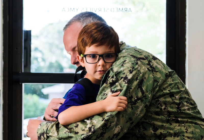 A navy service member hugs his young son