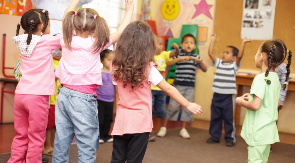 Preschool students jumping and dancing around having fun
